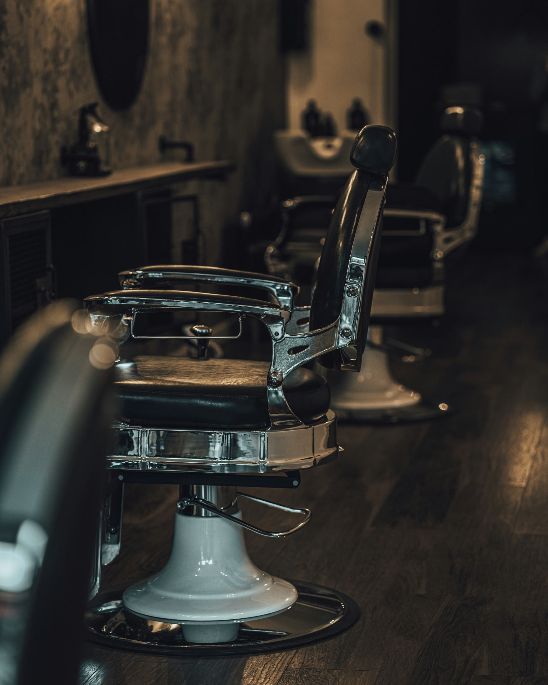Los sillones de la barbería en penumbra, alineados frente al espejo